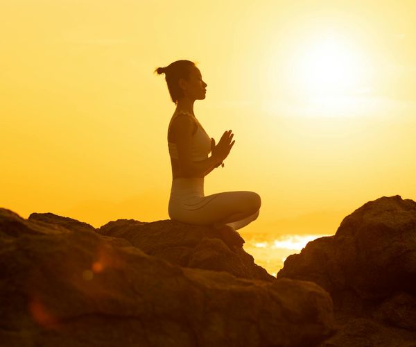Silhouette of a person in a stable mountain yoga pose.